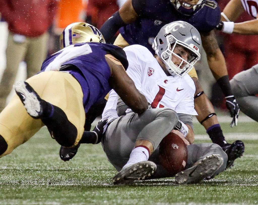 Washington Huskies linebacker Keishawn Bierria tackles Washington State Cougars quarterback Luke Falk and forces a fumble Saturday night during the 110th Apple Cup at Husky Stadium in Seattle November 25, 2017. Washington won 41-14. (Kevin Clark / The Herald)