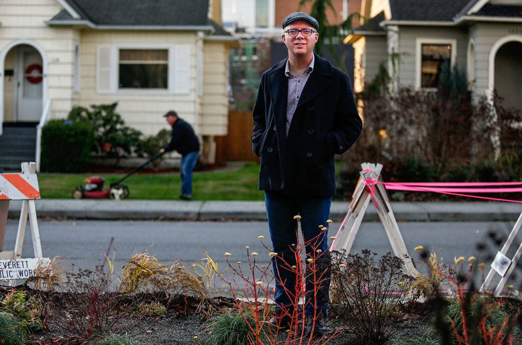 North Everetts Patrick Hall stands in his new rain garden as a neighbor mows his more traditional yard just across the street. (Dan Bates / The Herald)