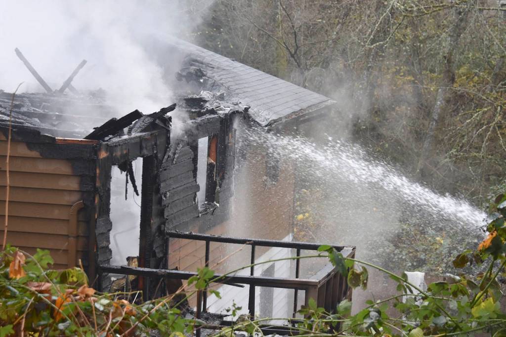 Firefighters douse a home in Lynnwood where a man was found dead in his garage on Wednesday. (Ian Terry / The Herald)