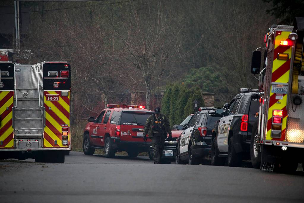 Fire and law enforcement vehicles line 16th Place W in Lynnwood near a home that burned down on Wednesday. (Ian Terry / The Herald)