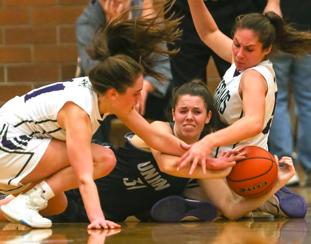 Edmonds-Woodways Ingrid Fosberg (left) and teammate Mia Dickenson (right) scramble with Unions Kaneyl Carpenter (center) for a loose ball at Mountlake Terrace High School on Dec. 27. (Kevin Clark / The Herald)