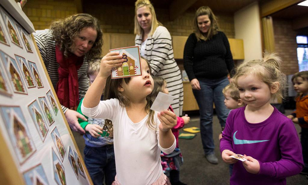 Harper Ninaud, 3, holds up her matching letters as parents and their toddlers enjoying reading, songs and activities at the Lake Stevens Library on Dec. 19. (Andy Bronson / The Herald)