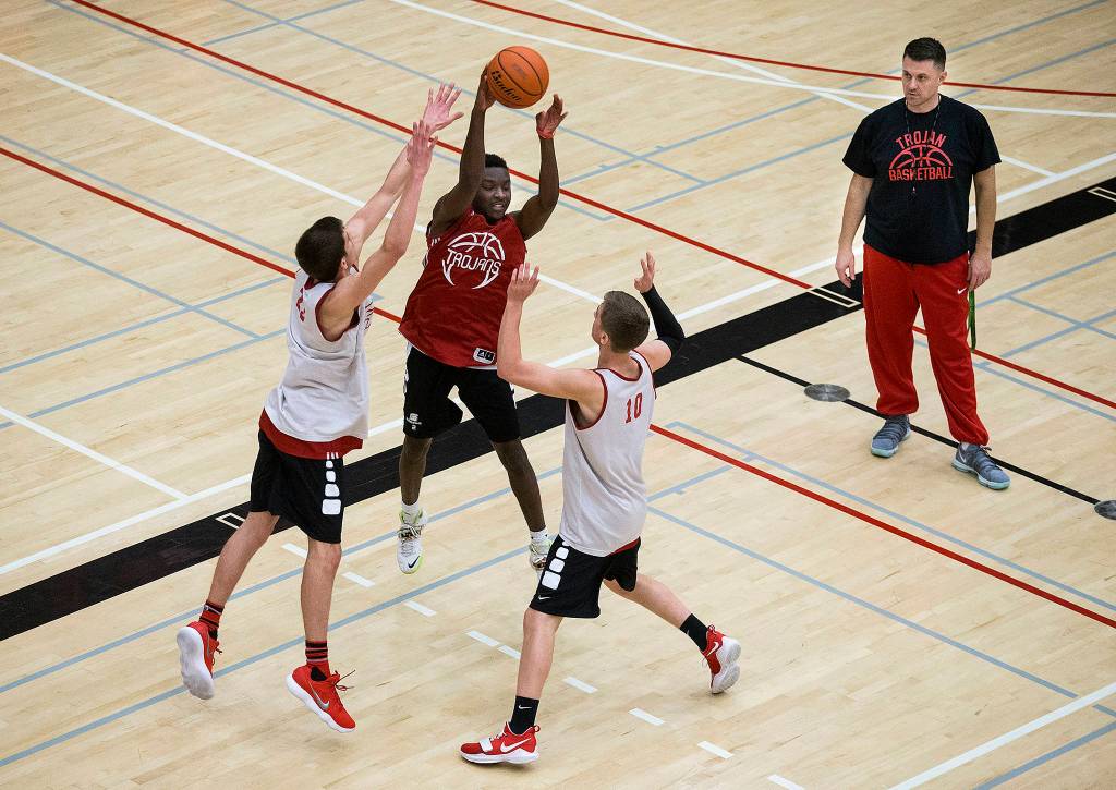Everett Community College mens basketball head coach Mike Trainman watches as Gio Jackson (center) throws a pass during practice in the Walt Price Student Fitness Center gymnasium on Dec. 26 in Everett. (Andy Bronson / The Herald)