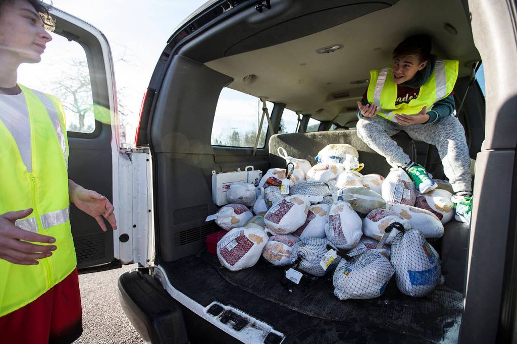 Cascade High School students Josh Westerfield (left) and Jaxon Roberts load frozen turkeys into the back of a van during the schools annual food drive on Wednesday. (Ian Terry / The Herald)