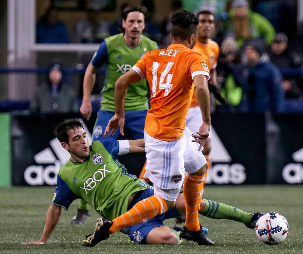 Seattles Nicolas Lodeiro slides to dislodge the ball from Houstons Alex in the first half of the Western Conference Finals at CenturyLink Field in Seattle on Nov. 30. (Kevin Clark / The Herald)