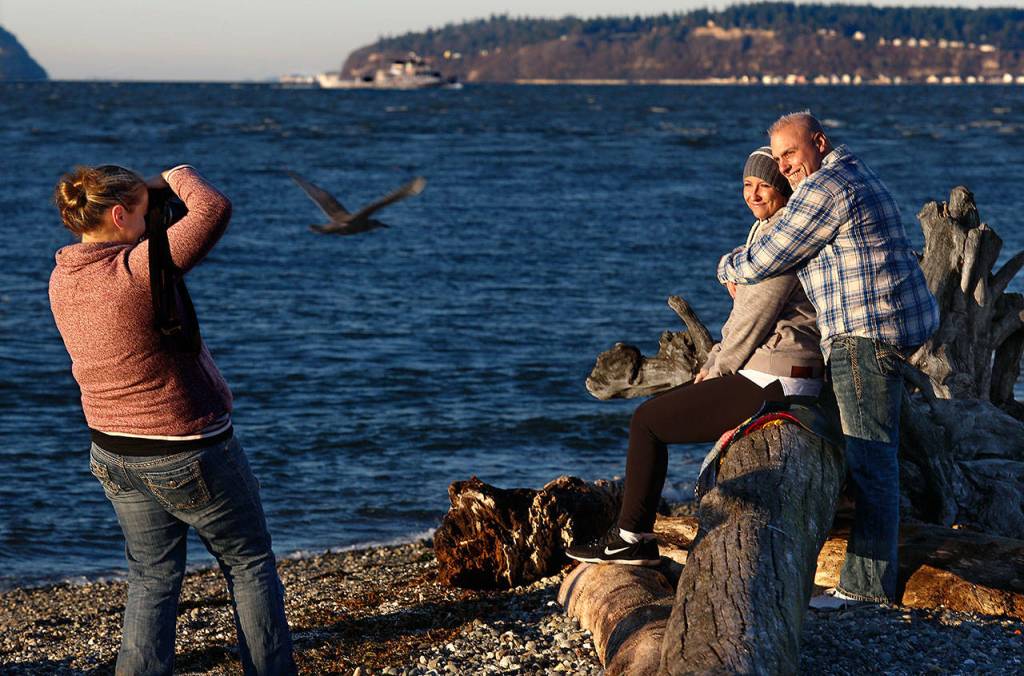 A friend of Heather Lopez, photographer Tessa Burrus (left), takes some nice photographs of Heather and her fiance Jimmy Absher at the Mukilteo beach. The couple have moved their wedding from April to Dec. 17 in light of recent news that Heather, first diagnosed with cancer in 2016, has more brain tumors. Her doctor has advised her to do things that matter, and to do them soon. (Dan Bates / The Herald)