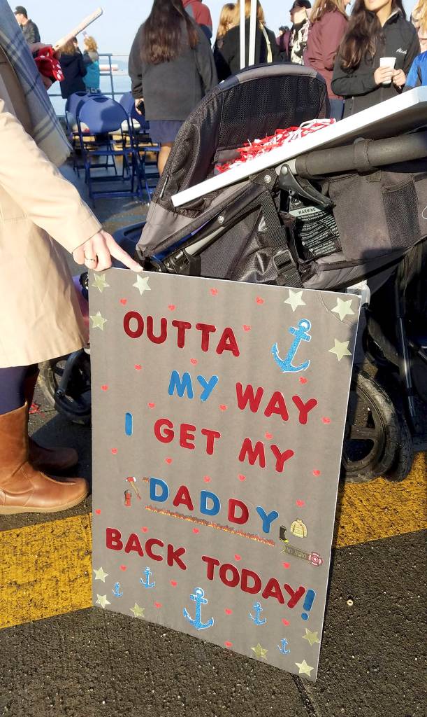 Jennifer Misner of Everett holds a sign steady for her 2-year-old daughter (in the stroller). They were at Naval Station Everett on Sunday morning to greet Misners husband, Zach Misner, who was returning from a six-month deployment on the USS Kidd. (Sharon Salyer / The Herald)