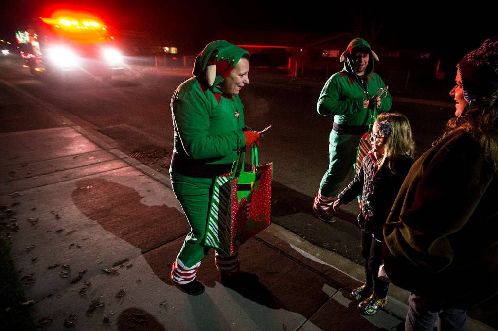 Dressed as elves, volunteer firefighters Angela Botamanenko (center) and Tim Ziesemer (right) hand out candy canes during a Christmas Parade on the streets of Darrington on Tuesday, Dec. 12. (Ian Terry / The Herald)