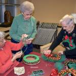 Aleph Swanson (from left), Pearl Hebert and Marilyn Carter work to complete a candy wreath at a recent work party for the AOK Club at the Washington Oakes Retirement Community in Everett. The finished wreaths are sold to benefit local charities. Its just one of the clubs year-round activities to support local nonprofits. (Melissa Slager / The Herald)