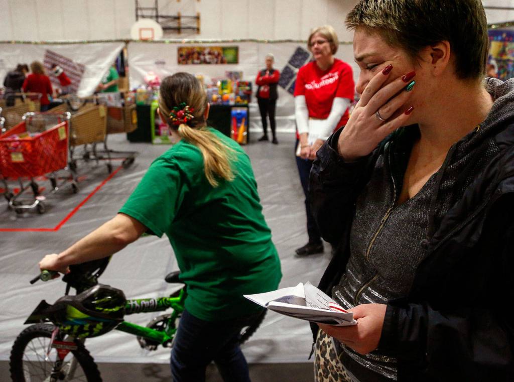 Barbara Diaz, 25, reacts with tears at Christmas House last week after a volunteer brought her a bicycle to take home to her family. (Dan Bates / The Herald)