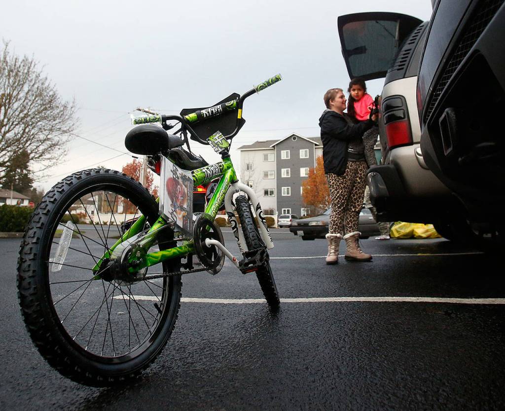 Outside Christmas House last week, Diaz lifts a young daughter to see the gift their family was given. (Dan Bates / The Herald)
