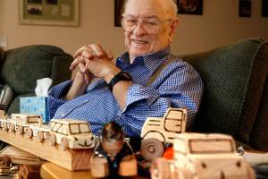 Leroy McVay, 85, of Everett makes wooden toys to donate to Volunteers of America. He uses a wood-burning pen to write Santas Workshop, Everett Division on the bottom of all his trucks and trains. (Dan Bates / The Herald)