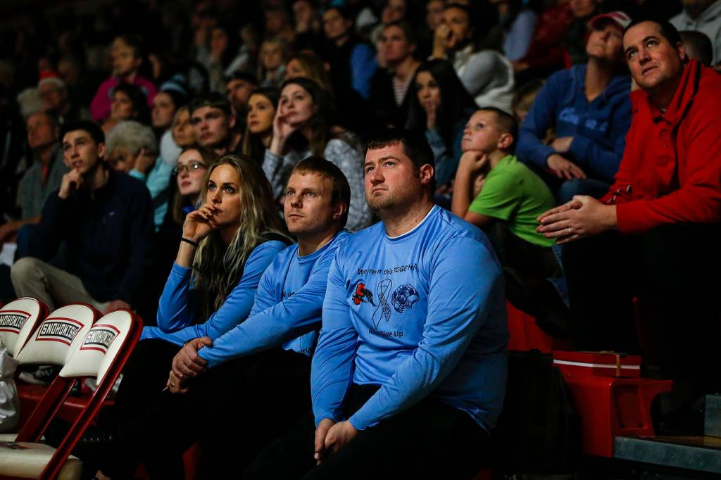 Snohomishs coaching staff, wearing blue, watches a tribute slideshow for Russ Roberts at halftime of a game between Snohomish and Glacier Peak on Dec. 19, 2017, at Snohomish High School. Roberts, a former Snohomish teacher and coach, passed away this year from prostate cancer. (Ian Terry / The Herald)