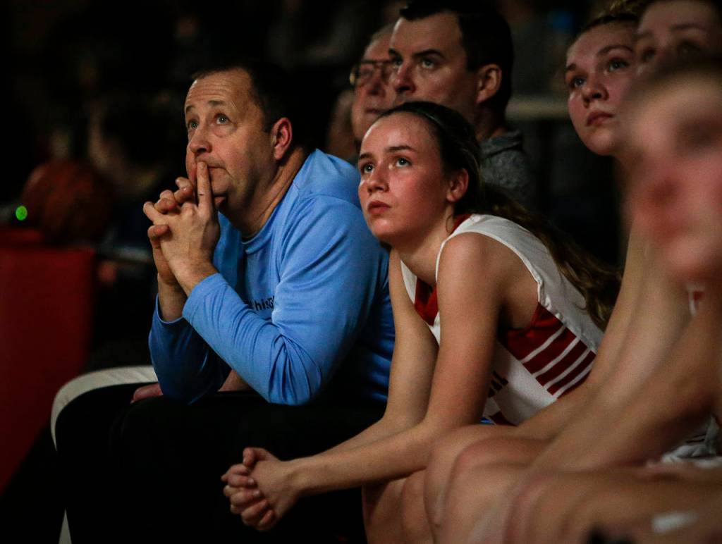 Snohomish head coach Ken Roberts (left) watches a tribute slideshow for his late father, Russ Roberts, during halftime of a game against Glacier Peak on Dec. 19, 2017, at Snohomish High School. (Ian Terry / The Herald)