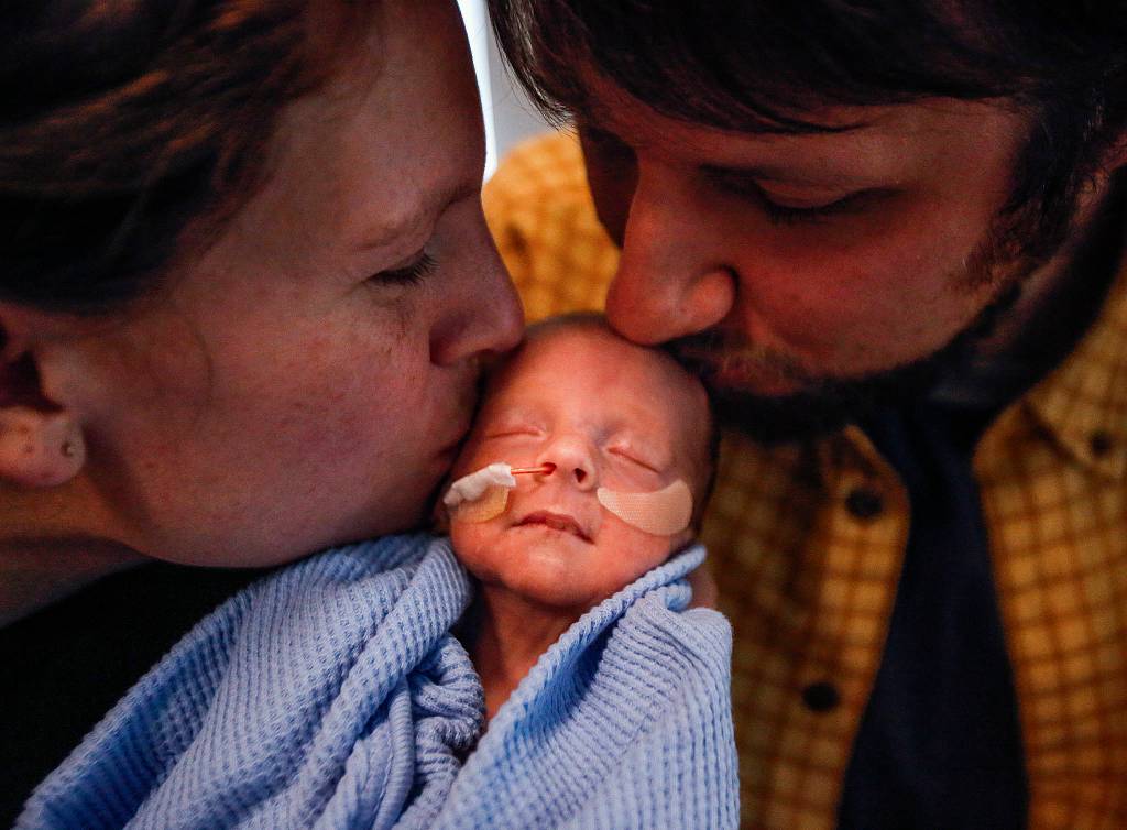 Elisabeth Strom and her husband, Steve Strom, kiss their son Hugo, who was born on the way to the hospital Dec. 2, at 30 weeks. He weighed 3 pounds, 11.6 ounces. (Dan Bates / The Herald)
