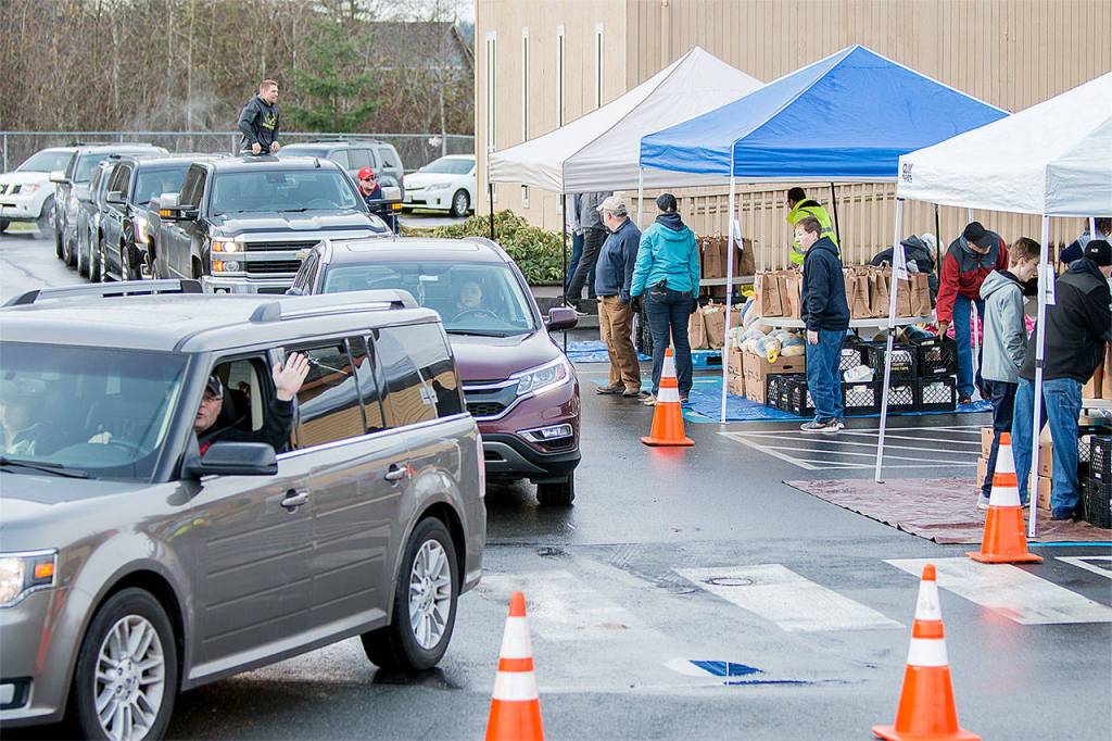 A few of the more than 50 volunteer drivers circle the building in line to load food for the holidays at Advent Lutheran Church in Mill Creek. (Photo by Bill Trueit)