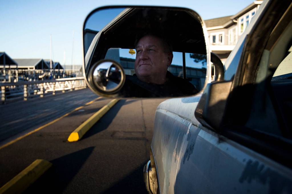 Mike Hestekind looks out the window of his truck near the Port of Edmonds on Feb. 13. A graduate of Seattles Ballard High School in 1972, Hestekind had recently lost a childhood friend and decided to honor him by driving around the North Puget Sound area, snapping photos in the sun and thinking of some of the best memories they had together. (Ian Terry / The Herald)