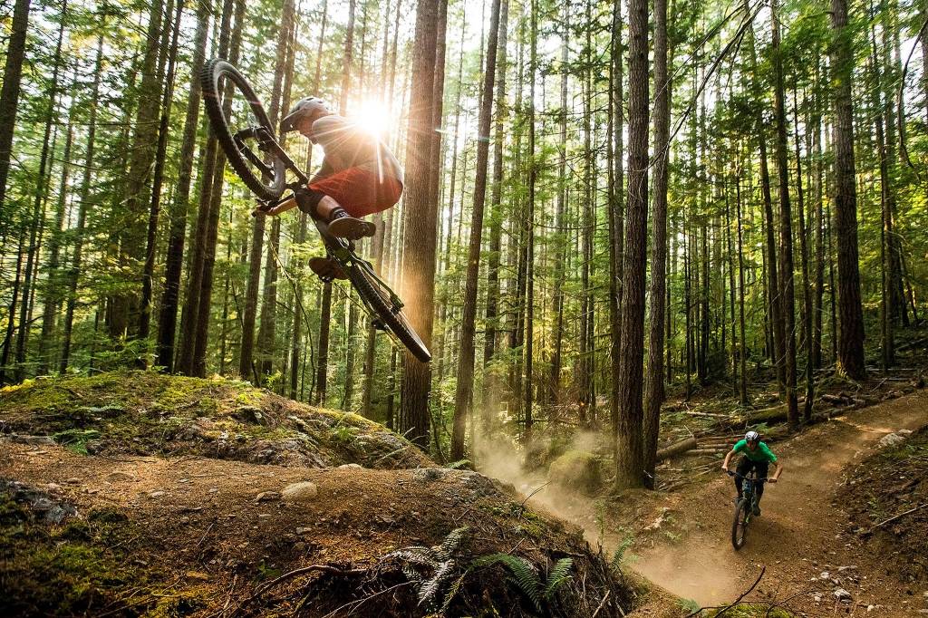 Skye Schillhammer (left) catches air off a rocky lip as Oliver Parish exits a corner on Darringtons new mountain bike trail system at the base of North Mountain, on Aug. 10. Schillhammer grew up in Darrington and now resides in Bellingham, where he works for Transition Bikes, a mountain bike manufacturer. (Ian Terry / The Herald)