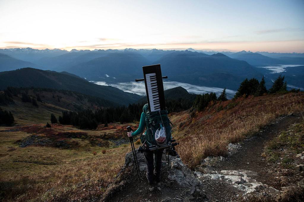 With her Yahama Piaggero keyboard in her backpack, Rose Freeman stops for a moment to take in the view during an early morning ascent of Sauk Mountain, near Concrete, on Oct. 5. Freeman and Anastasia Allison play violin and piano at sunrise on Cascade peaks. They go by the name The Musical Mountaineers. (Ian Terry / The Herald)