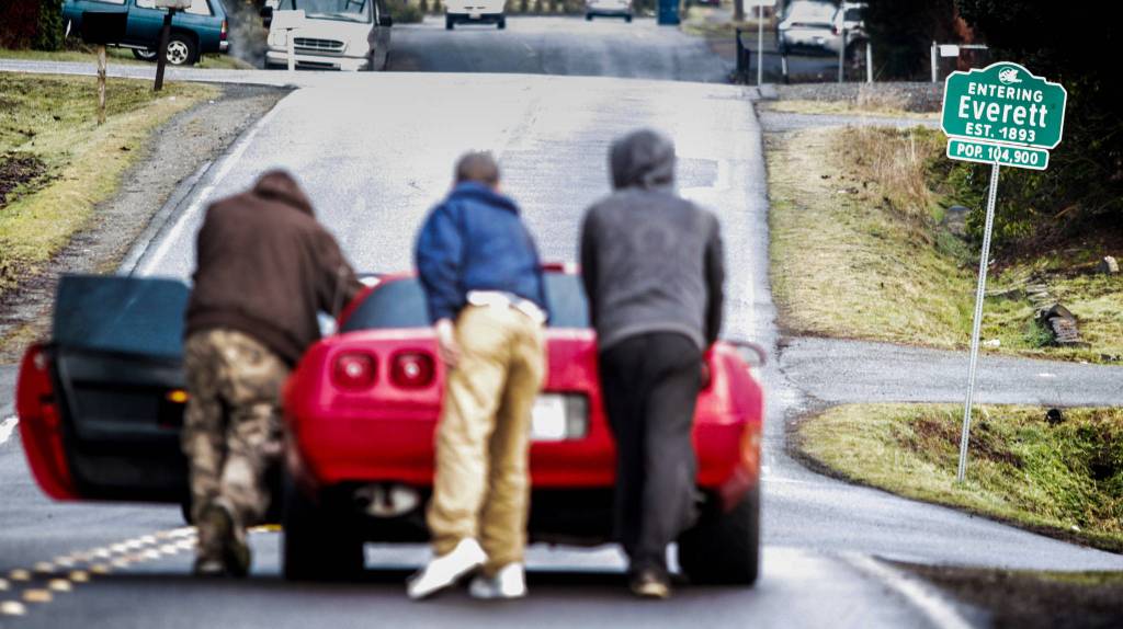 Men evicted from a home filled with squatters push a Chevrolet Corvette down Second Avenue Southeast in Everett on Jan. 26. The Snohomish County Sheriffs Office estimated that as many as 21 people had been staying at the three-bedroom house. When deputies arrived to serve a notice of eviction, they found piles of hypodermic needles in the driveway. (Ian Terry / The Herald)