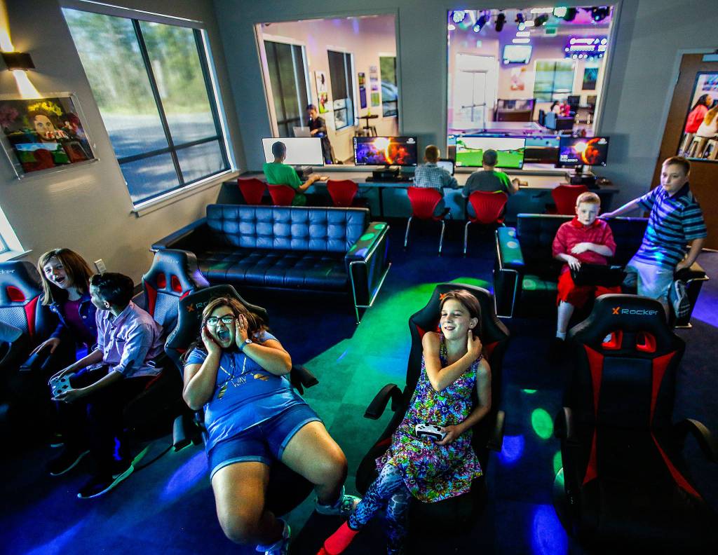 Mostly middle-school kids enjoy playing games on big-screen TVs Sept. 14 at the new Teen Center at the Lake Stevens Boys & Girls Club. Facing, from left, are Riley Gentry, 12; Ayden Perez, 11; Emma Price, 11; Reegan Pauley, 11; Evan Geil, 11; and his twin brother, Drew Geil, 11. (Dan Bates / The Herald)