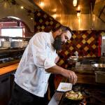 Lombardis Executive Chef Andy Hilliard sprinkles herbs on vegetables as he makes a 40 Clove Chicken entree. (Andy Bronson / The Herald)