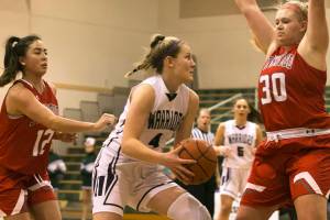 Edmonds-Woodways AJ Martineau drives past Stanwoods Kayla Frazier, left, and Stanwoods Kaitlin Larson, right, Wednesday night at Edmonds-Woodway High School in Edmonds on January 3, 2018. Edmonds-Woodway won 73-67. (Kevin Clark / The Daily Herald)