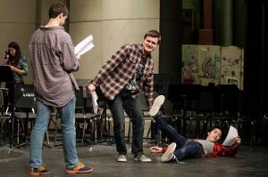 Kamiak student Aidan Norris (center) drags Matthew Ninh into a scene as Mitchell Beard (left) reads his lines. (Ian Terry / The Herald)
