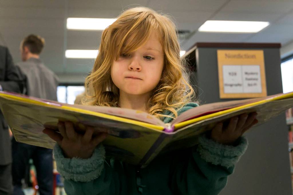 Paisley Molnick, 5, reads a book during the grand opening of the new Lakewood/Smokey Point Library in Arlington on Jan. 6. (Kevin Clark / The Daily Herald)