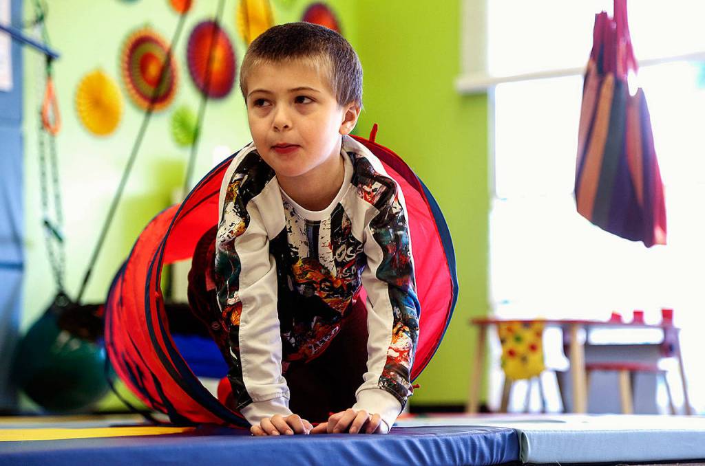 Hunter Standley, 6, crawls through a long fabric tunnel Friday at Wee Fit, Hunter, who is autistic, is with his mom, Breanna Standley, 25, and his grandmother, Barbara Bambrick, 63. They are from Tulalip. (Dan Bates / The Herald)