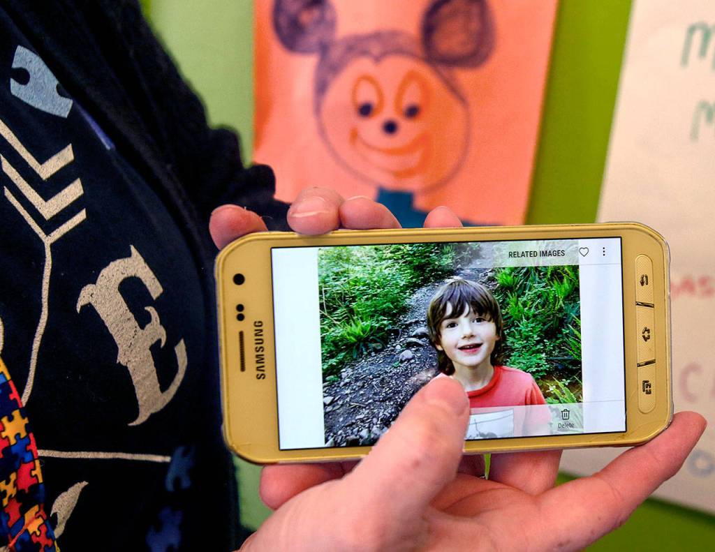 Wee Fit co-owner Melissa Wren holds up a cellphone picture of her son, Cooper, 6, who has autism. Pictures drawn by Cooper are hanging in several places around Wee Fit. (Dan Bates / The Herald)
