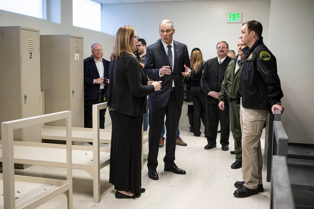 Gov. Jay Inslee (center) talks with law enforcement and health officials as he tours Snohomish Countys former work release building in downtown Everett on Thursday. (Ian Terry / The Herald)