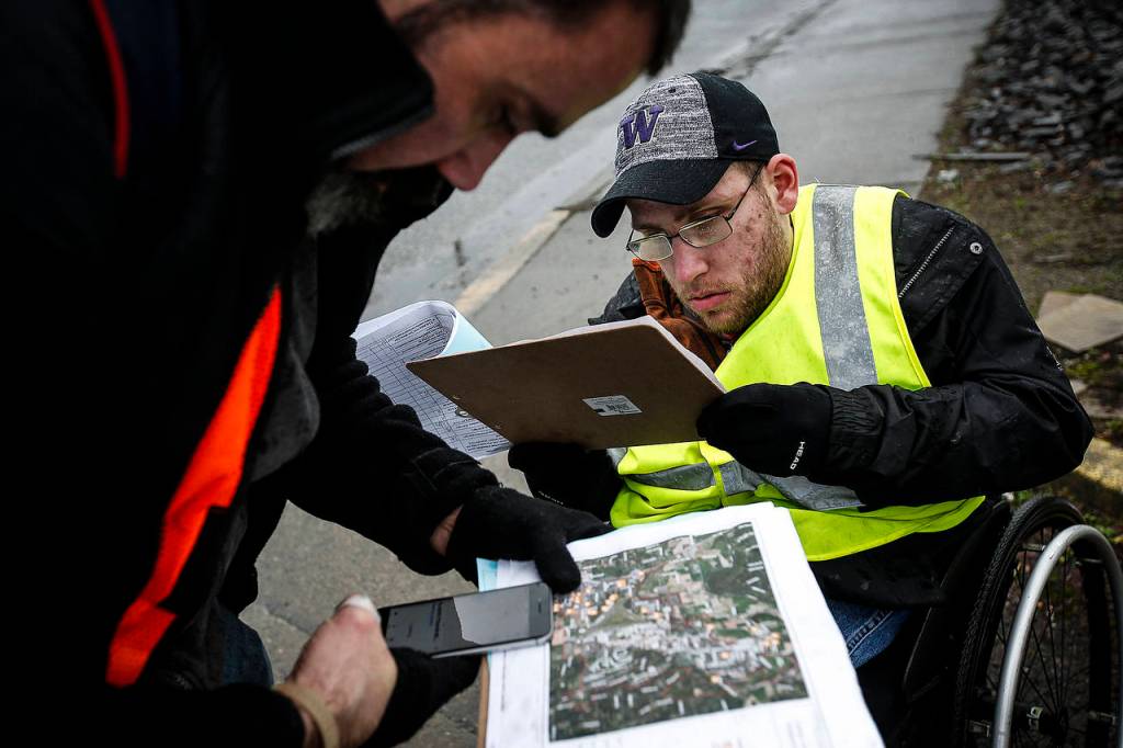 Tyson Kuntz (right), a volunteer with AmeriCorps, and Paul Olson, check maps while out in the Smokey Point area surveying the homeless population Tuesday. (Ian Terry / The Herald)