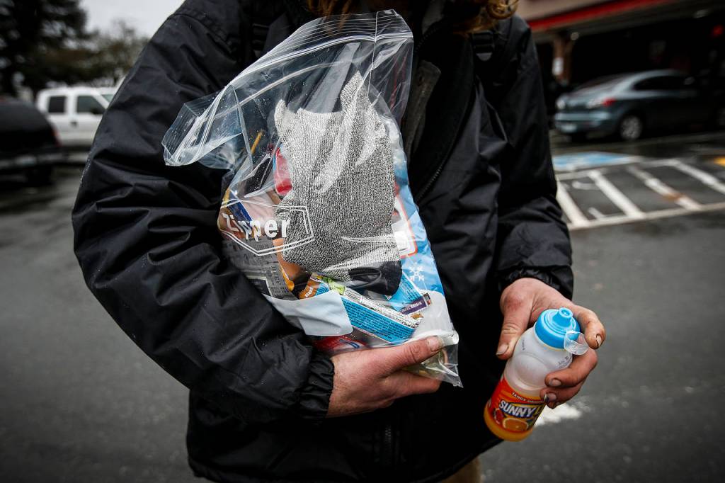 Scott Armstrong holds supplies including clean socks, toiletries and snacks given to him by volunteers Tuesday in Arlington. (Ian Terry / The Herald)