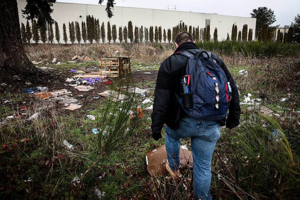 Volunteer Paul Olson, of Everett, walks through a former homeless encampment near Smokey Point Boulevard on Tuesday. (Ian Terry / The Herald)