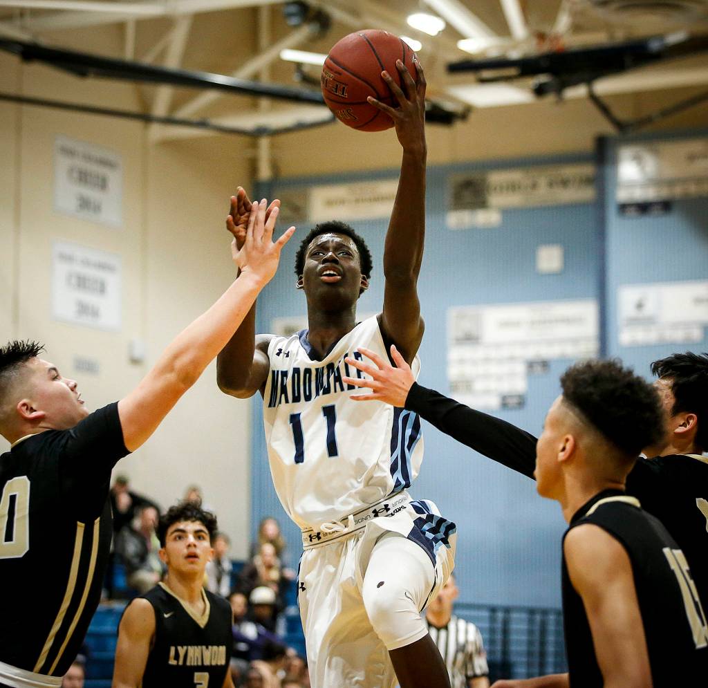Meadowdales Mustapha Sonko (center) drives through a host of Lynnwood defenders for a layup during a game at Meadowdale High School in Lynnwood on Jan. 16. (Ian Terry / The Herald)