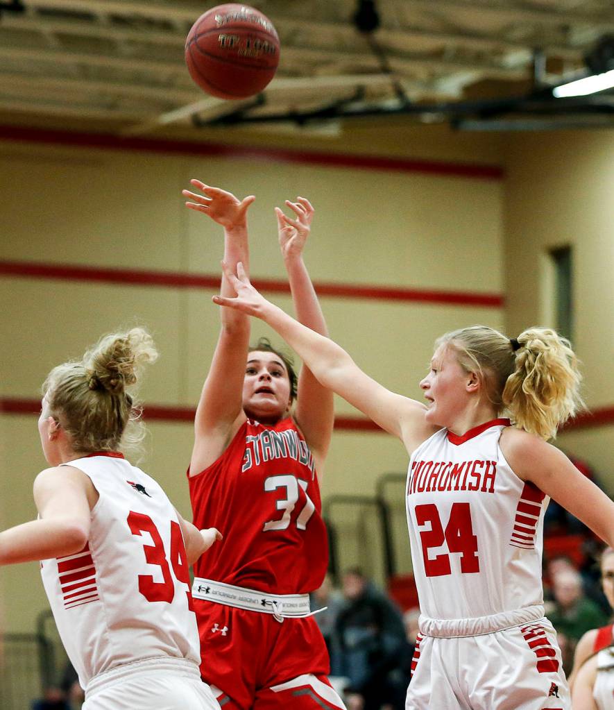 Stanwoods Madison Chisman (center) takes a shot between Snohomish defenders Kyra Beckman (left) and Kaylin Beckman (right) during a game Jan. 24, 2018, at Snohomish High School. (Ian Terry / The Herald)