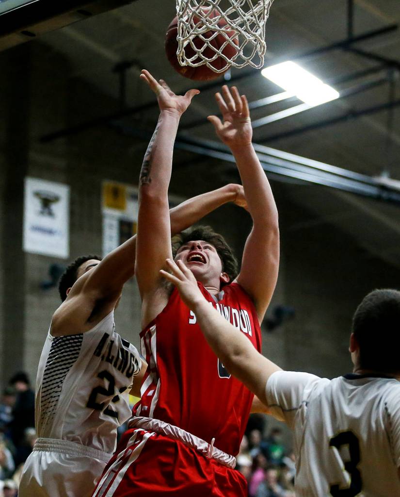 Stanwoods Mitch Jones (center) takes a shot during a game against Arlington on Jan. 26, 2018, at Arlington High School. (Ian Terry / The Herald)