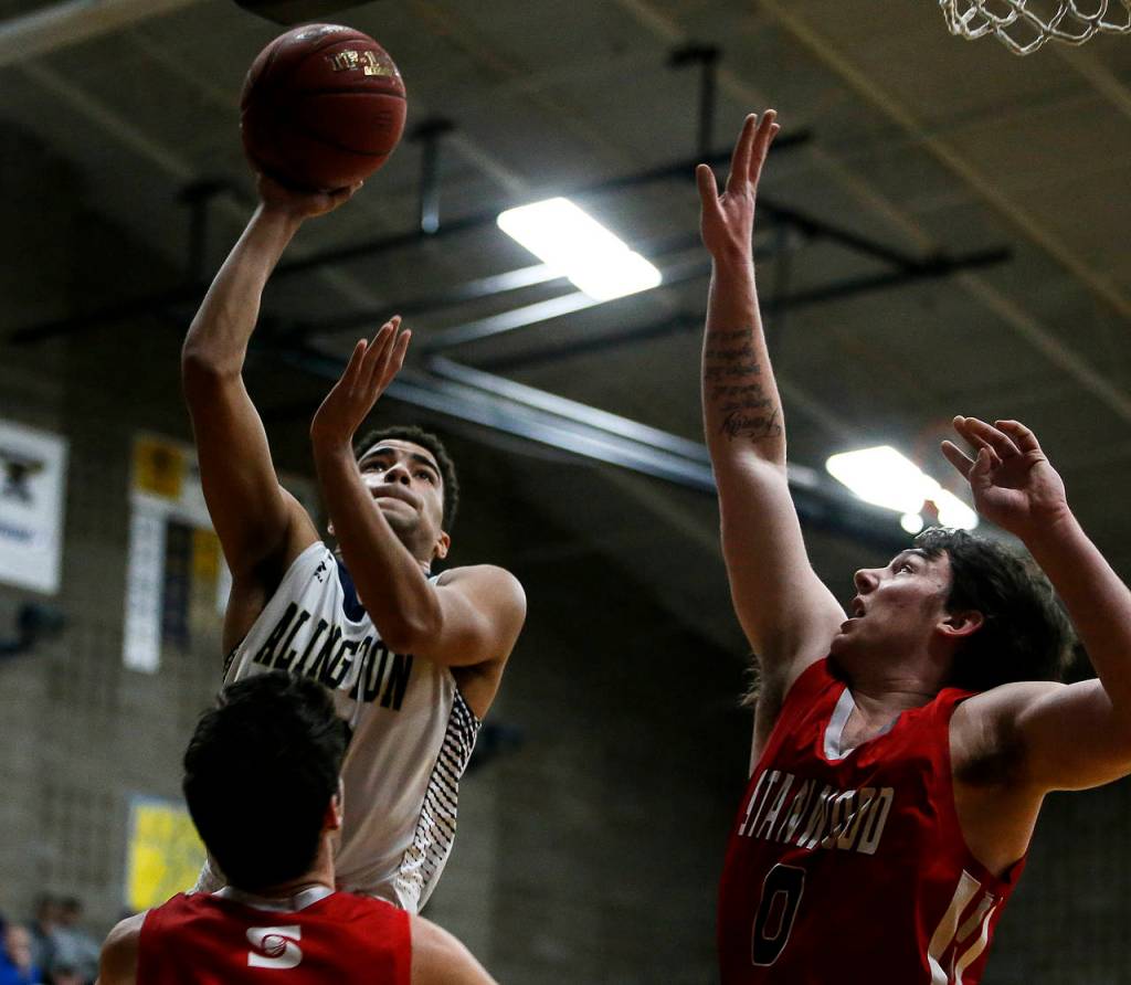 Arlingtons Ayodele Aribibola (left) takes a shot as Stanwoods Mitch Jones (right) defends during a game on Jan. 26, 2018, at Arlington High School. (Ian Terry / The Herald)
