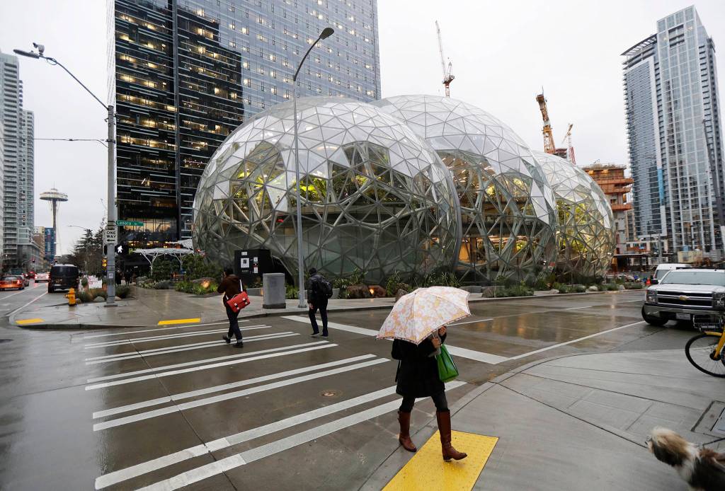 Pedestrians walk past the Amazon Spheres in downtown Seattle on the day of the grand opening of the geodesic domes, which will primarily serve as a working and gathering space for Amazon.com employees, Monday in Seattle. (AP Photo/Ted S. Warren)
