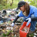 In this Nov. 2017 photo, Steph Gaspar, a volunteer outreach worker with The Hand Up Project, an addiction and homeless advocacy group, cleans up needles used for drug injection that were found at a homeless encampment in Everett. (AP Photo/Ted S. Warren)