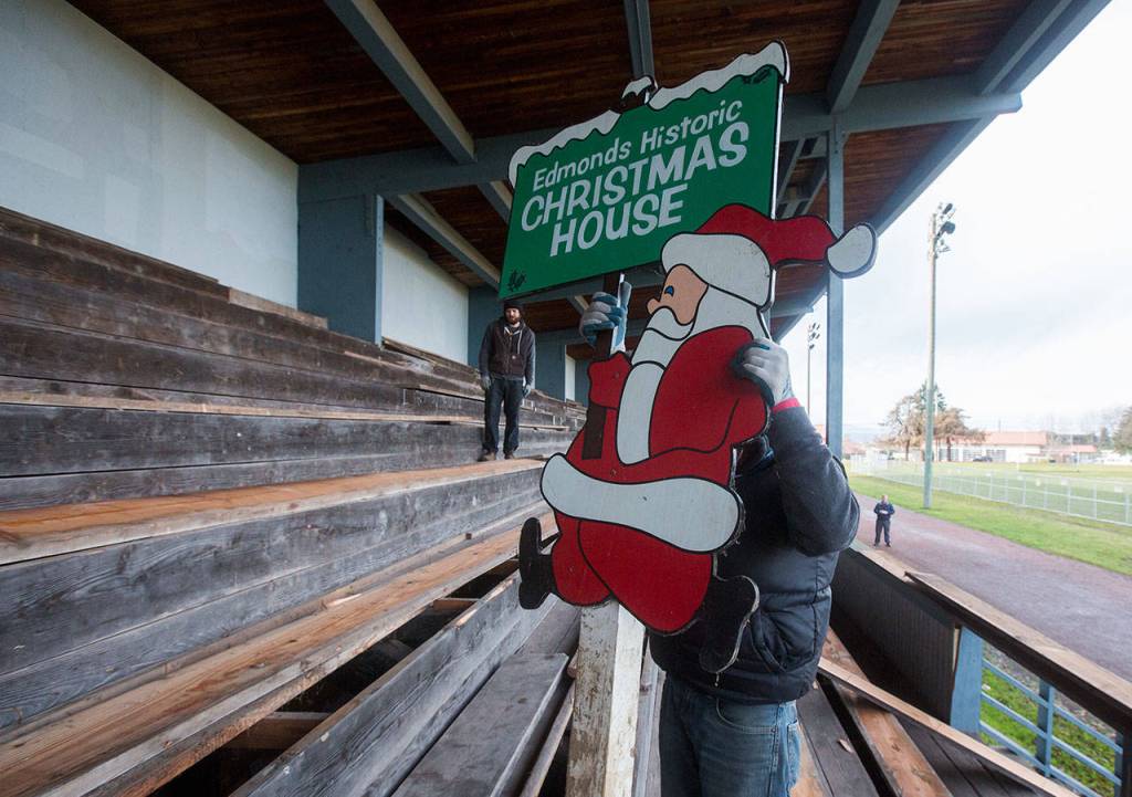 Ballard Reuse salvage manager Joel Blaschke pulls out a Christmas sign from below the boards at the former Edmonds High School stadium Tuesday in Edmonds. (Andy Bronson / The Herald)