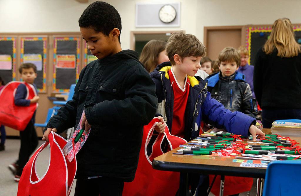 Emerson Elementary School third-graders Gavin Walcott (nearest) and Curtis Walker (near right) place gifts in Buddy Bags that they will give to people living in a local nursing home. (Dan Bates / The Herald)