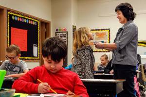 In Snohomish, Emerson Elementary School third-grade teacher Kim Moritz looks at and compliments a Valentines Day card made by Destiny Hawes, 8, while other students, including Evan Jackson, 9, (front) and Austin Drake, 8, (left) work to finish their own cards to place in buddy bags and give to people living in a local nursing home. (Dan Bates / The Herald)