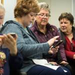 Gretchen Mork (right) watches as Connie Castruita (center) swipes close a bunch of open programs on her phone as they take a smartphone class at the Carl Gipson Senior Center on Thursday in Everett. (Andy Bronson / The Herald)