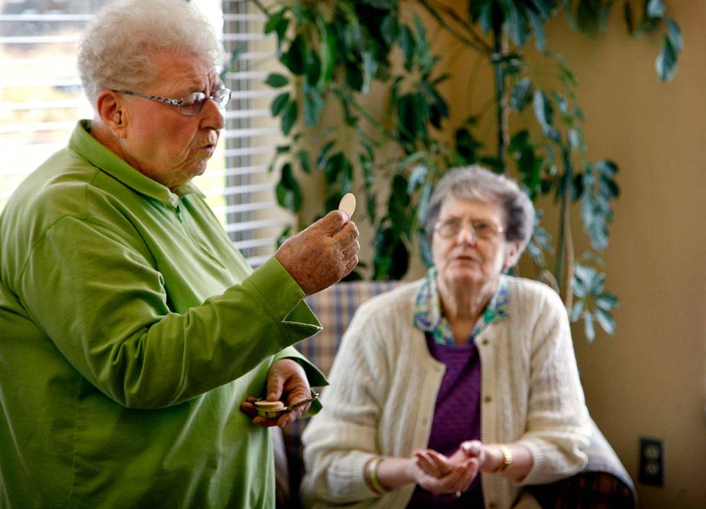 In July 2012, Sister Barbara Geib (left) of St. Mary of the Valley Catholic Church in Monroe delivers Communion to seniors and residents, including Alice Beach (back) at Regency Care Center in Monroe. At the time, Geib was celebrating her 60th year as a nun. (Dan Bates / The Herald)