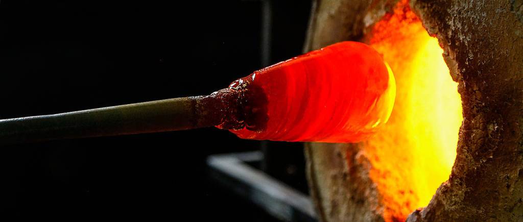 Ellinger super-heats a glob of glass in a 2,300-degree furnace at Glass Quest Studio. (Dan Bates / The Herald)