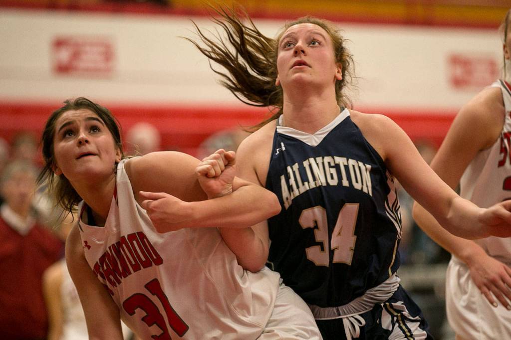 Stanwoods Madison Chisman (left) and Arlingtons Kelsey Mellick look to rebound on a free throw during a playoff game on Feb. 9, 2018, at Stanwood High School. (Kevin Clark / The Herald)