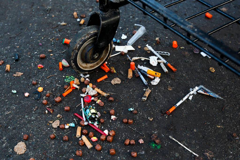 Hypodermic needles litter the driveway of a home in Everett used by squatters in 2017. (Ian Terry / Herald file)
