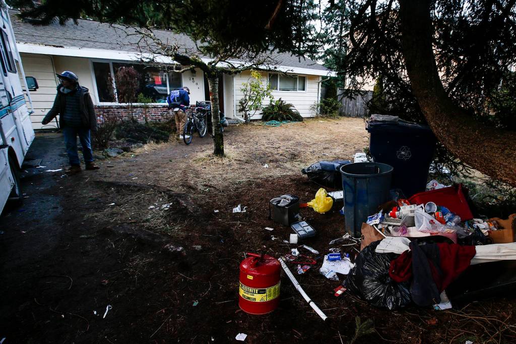 Trash is strewn about the front yard of a home used by squatters in Everett in 2017. (Ian Terry / Herald file)